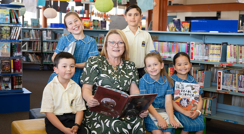 Principal Leanne Nettleton reading with students in the library at St Angela's Primary School Castle Hill