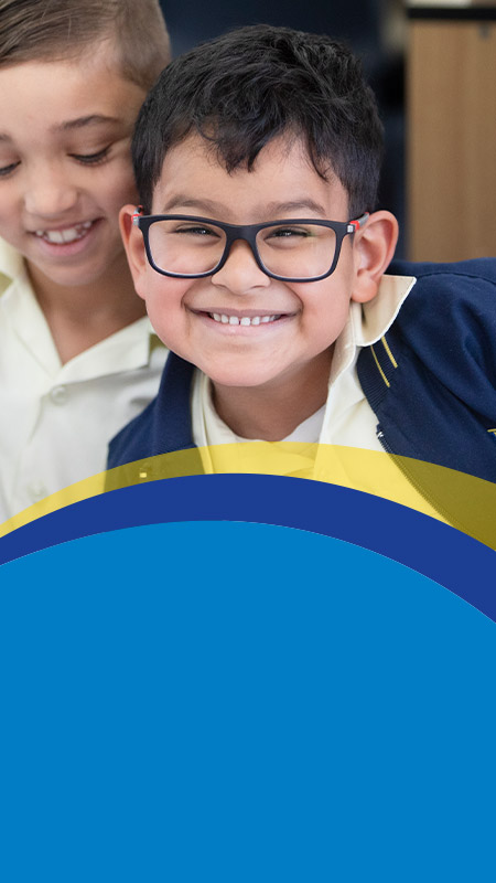 Student wearing glasses smiling in the classroom at St Angela's Primary School Castle Hill
