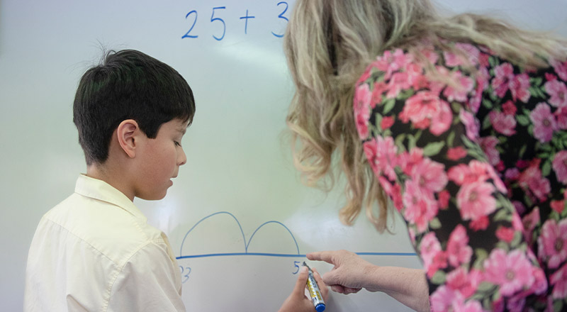 Student learning math in the classroom with his teacher at St Angela's Primary School Castle Hill