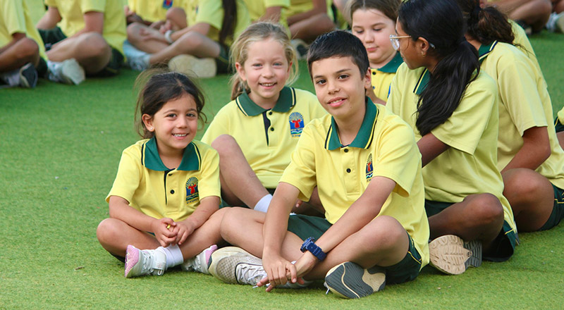 Students sitting together in the playground at St Angela's Primary School Castle Hill