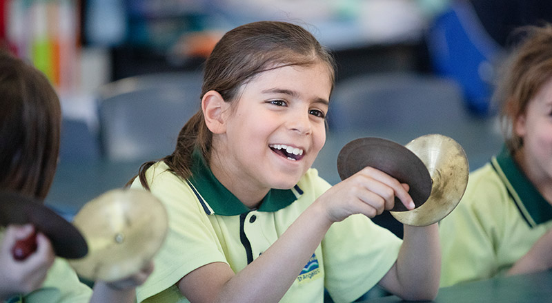 Student playing cymbals in the classroom at St Angela's Primary School Castle Hill