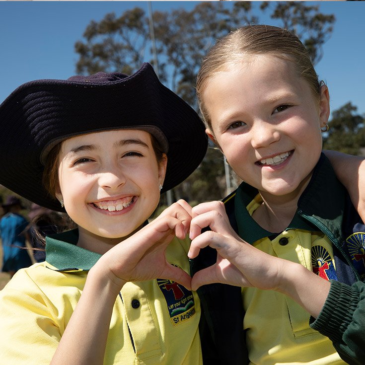 Students holding their fingers together to make a heart at St Angela's Primary School Castle Hill